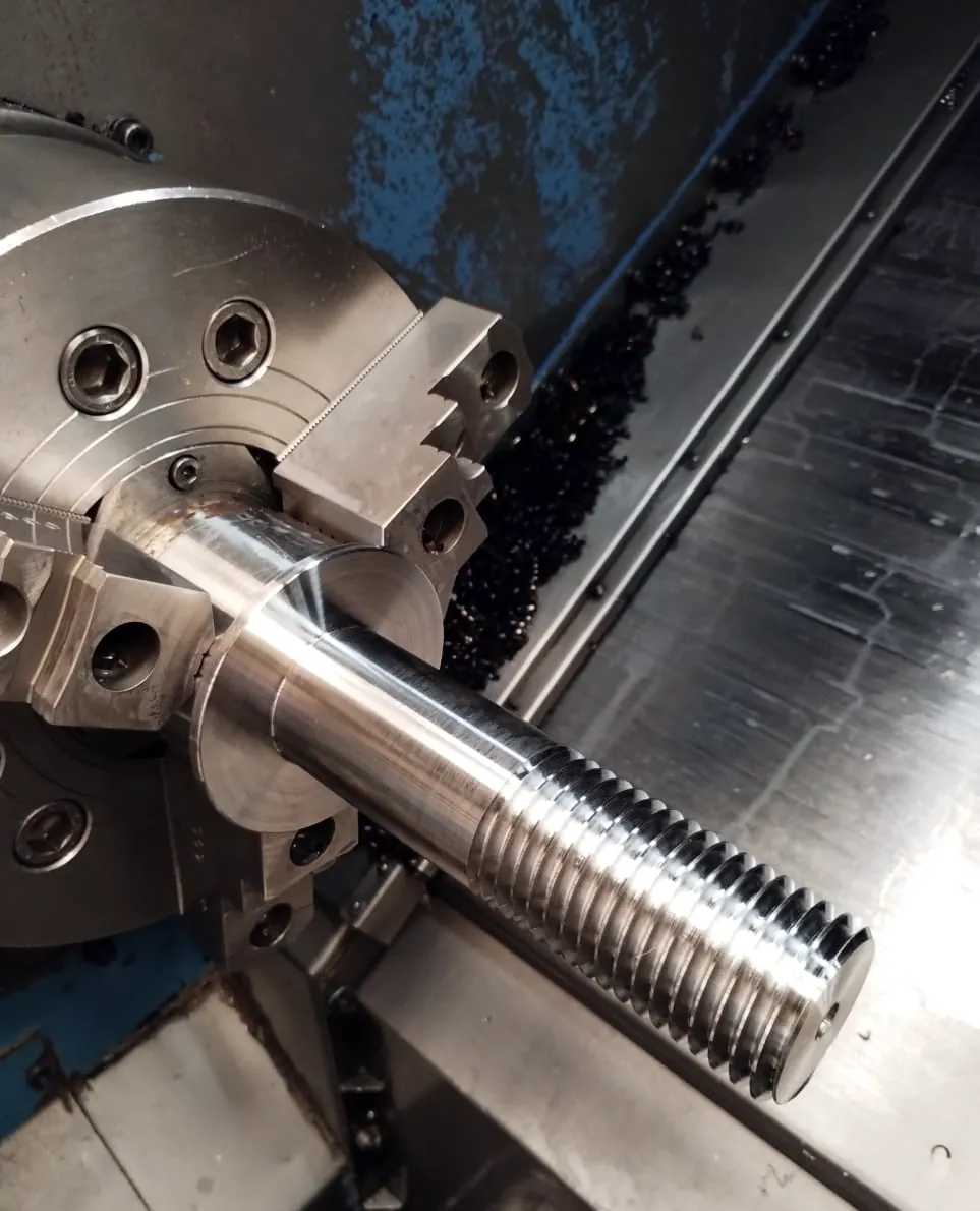 Torno CNC mecanizando un eje de acero inoxidable con rosca en el taller de LUCAMAR